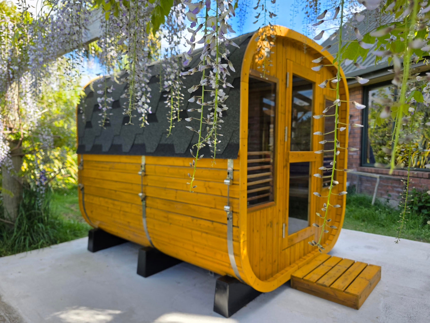 Wooden pod with a black roof in a garden setting